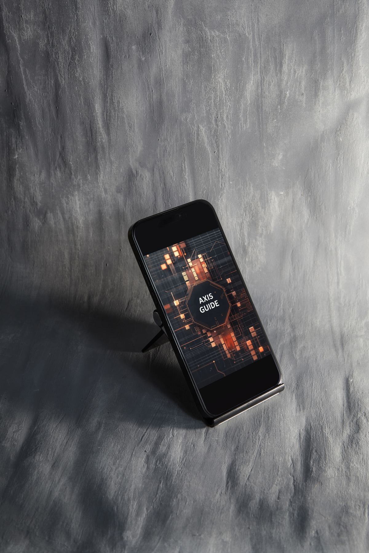 A black smartphone displayed on a small stand against a textured gray concrete wall. The phone screen shows an app or guide cover with the text 'APP GUIDE' over an orange and dark abstract pattern.